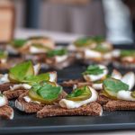 Delicious canapés with ham, pickles, and parsley on brown bread for a refreshing snack.